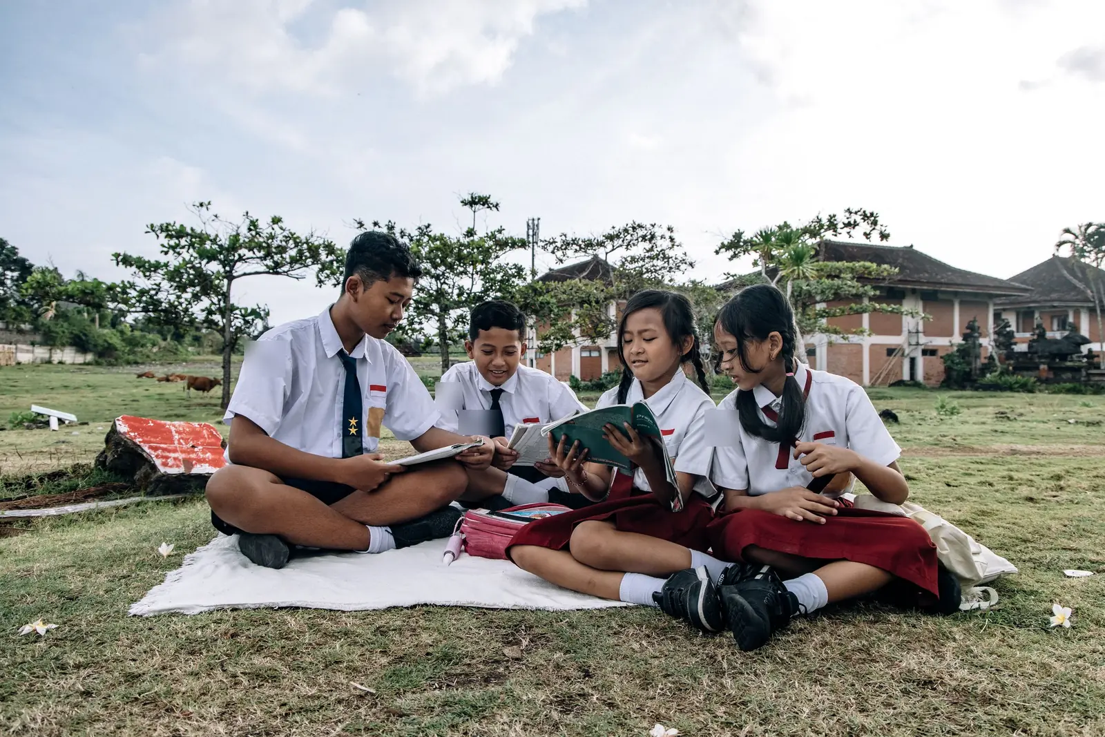 Grade school students in uniform reading books outdoors
